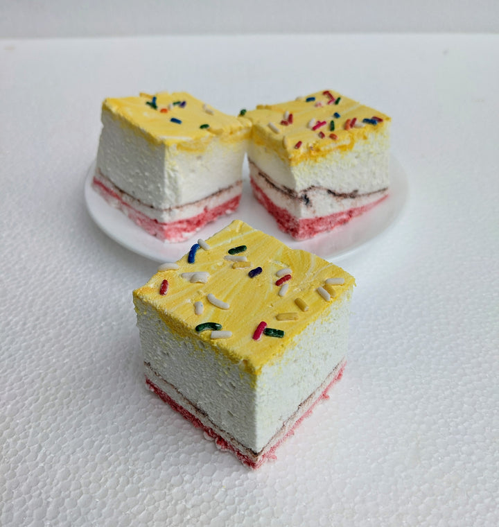 A close-up of three banana split gourmet marshmallows, arranged with one marshmallow in front and two slightly behind, creating depth against a clean white background. Each marshmallow is handcrafted in the USA, featuring yellow, red, and brown swirls that highlight the classic banana, strawberry, and chocolate flavors. Topped with colorful sprinkles, these best-in-class artisanal marshmallows showcase their soft, fluffy texture—perfect for desserts, s’mores, gifting, and luxury confections.