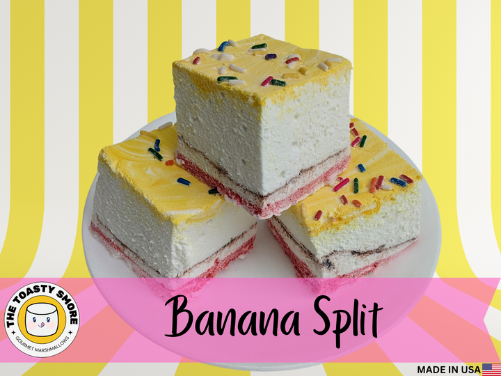 A close-up of three banana split gourmet marshmallows, each topped with colorful sprinkles. The marshmallows feature vibrant yellow, red, and brown swirls, representing banana, strawberry, and chocolate flavors. Their soft, fluffy texture is highlighted, making them look extra decadent. These handcrafted treats are perfect for desserts, s’mores, and gifting—a must-try for lovers of artisanal marshmallows and unique confections.