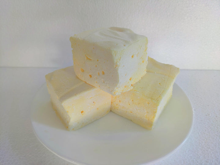 Three extra-large Butter Vanilla gourmet marshmallows made with organic marshmallow root and premium beef gelatin, displayed on a white plate against a plain white background.