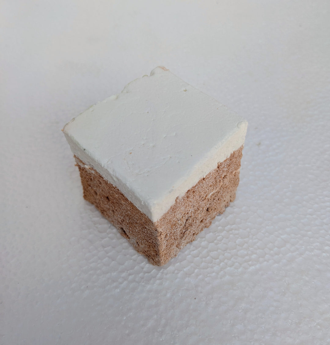 A single, golden Butterbeer marshmallow sits at the front of a clean, white plate, with two more fluffy cubes behind it. Its butterscotch shimmer catches the light, highlighting its pillowy texture. Handmade in the USA with premium gelatin and no corn syrup, this gourmet marshmallow is perfect for s’mores, snacking, or gifting. 
