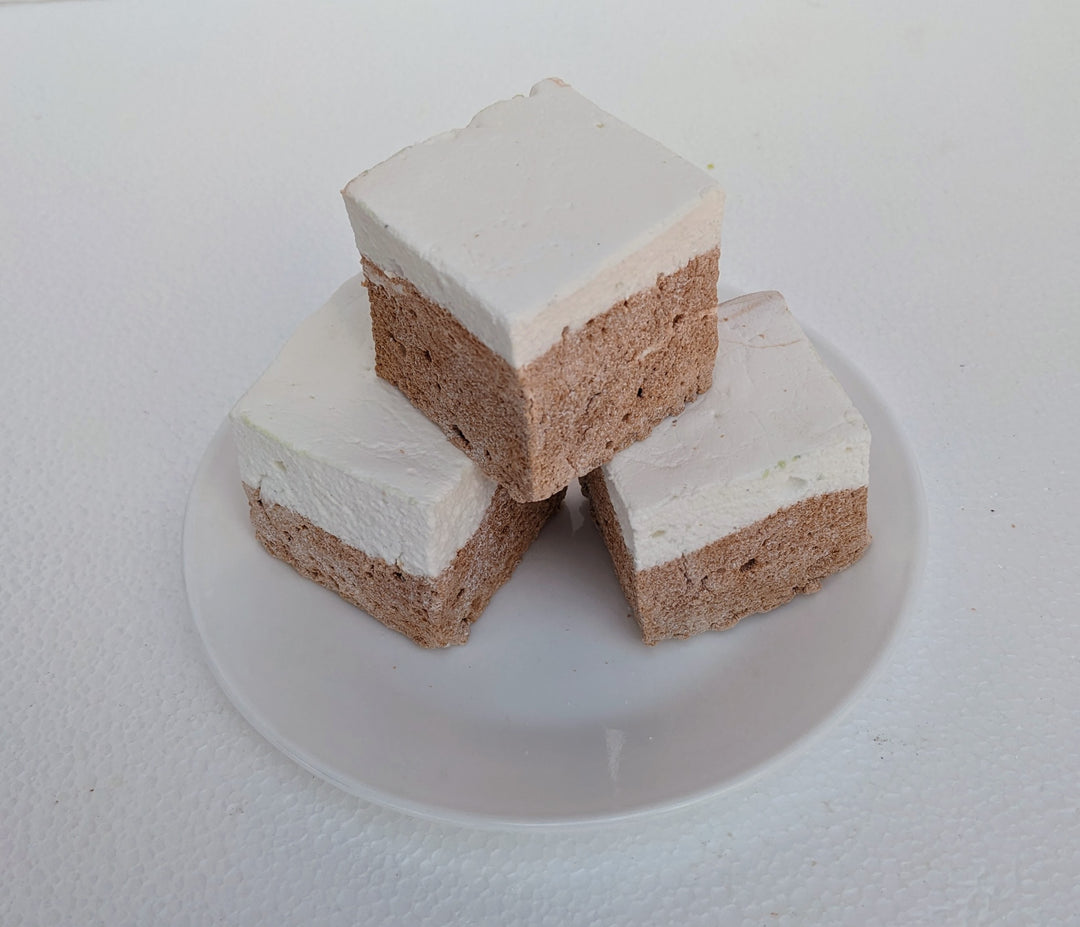 Three large, fluffy Butterbeer marshmallows sit on a clean, white plate, their golden butterscotch cubes gleaming with a light shimmer. Handmade with premium gelatin and no corn syrup, these gourmet marshmallows are perfect for s’mores, desserts, or gifting.
