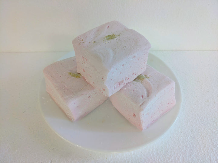 Champagne and Sugar marshmallows made with beef gelatin, organic marshmallow root, and no corn syrup, arranged on a white plate against a clean white background. The light pink handcrafted treats feature a soft texture and edible gold glitter, highlighting their celebratory appeal and clean-label ingredients.