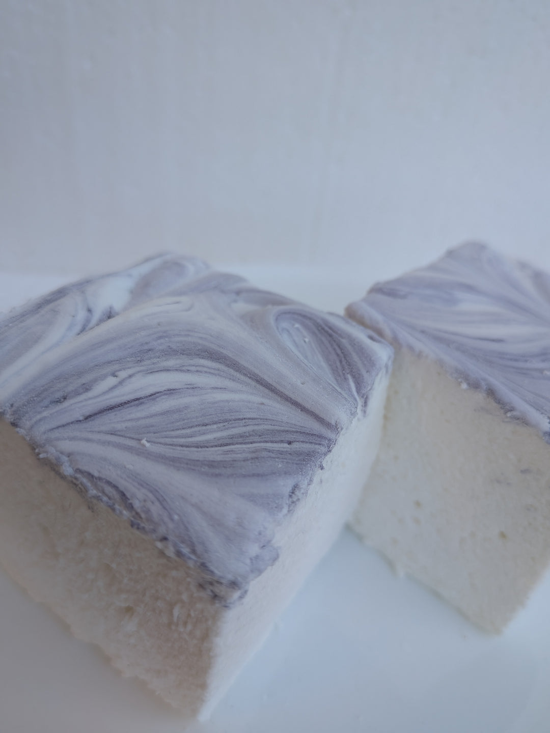 Close‑up of two gourmet marshmallows made in the USA with Halal‑certified beef gelatin, organic marshmallow root, natural dyes, no corn syrup, and gluten‑free ingredients from The Toasty S’more.