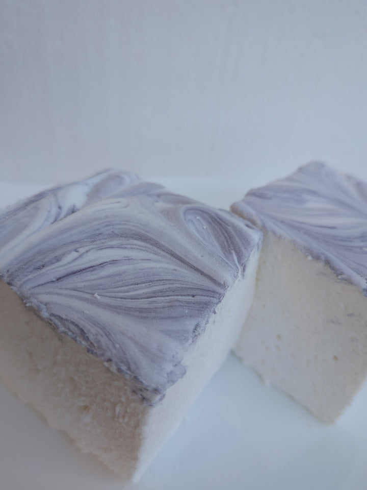 Close‑up of two gourmet marshmallows made in the USA with Halal‑certified beef gelatin, organic marshmallow root, natural dyes, no corn syrup, and gluten‑free ingredients from The Toasty S’more.