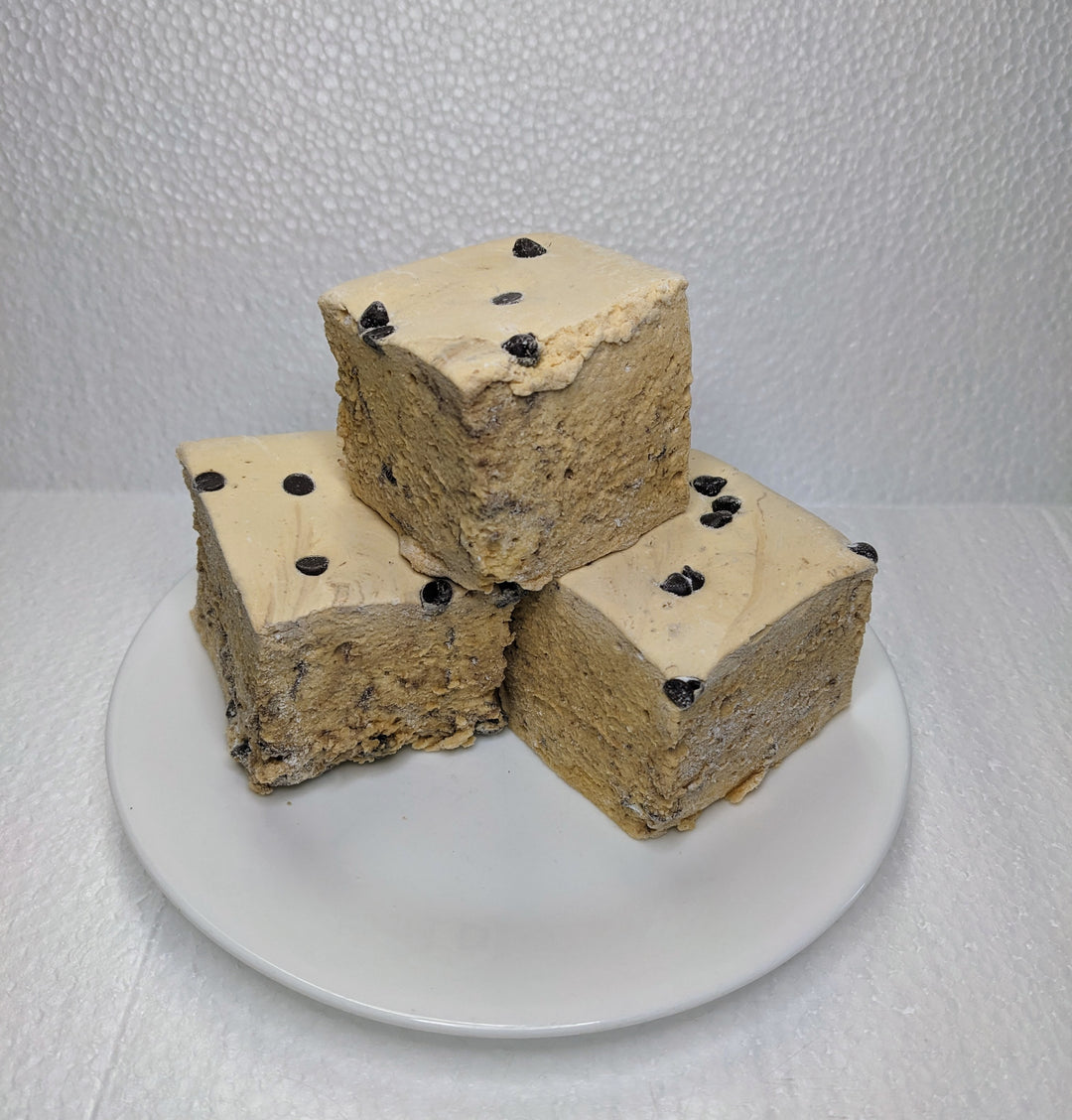 Three cookie dough marshmallows on a white plate, displayed on a clean, white background