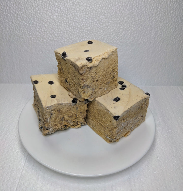 Three cookie dough marshmallows on a white plate, displayed on a clean, white background