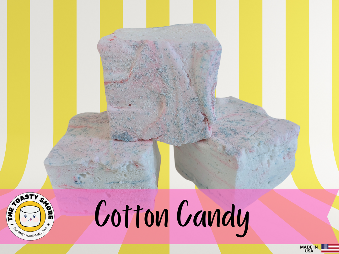 Three cotton candy marshmallows displayed on a yellow and white striped background. The marshmallows are featured alongside The Toasty Smore logo and a "Made in USA" flag