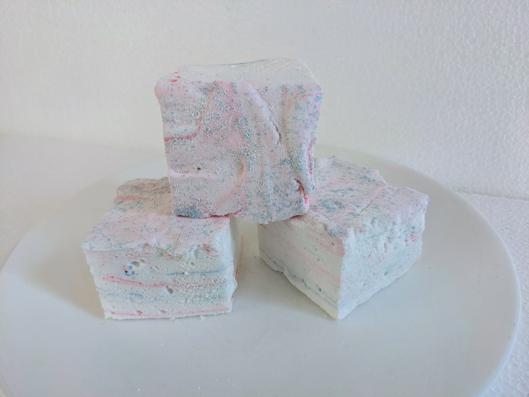 Three cotton candy marshmallows with swirls of pink and blue on a clean, white background.