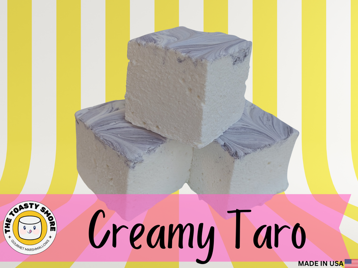 Three Creamy Taro marshmallows with white bases and swirled purple tops, photographed in front of a yellow and white striped background, made in the USA with Halal‑certified beef gelatin, organic marshmallow root, natural dyes, no corn syrup, and gluten‑free ingredients by The Toasty S’more.