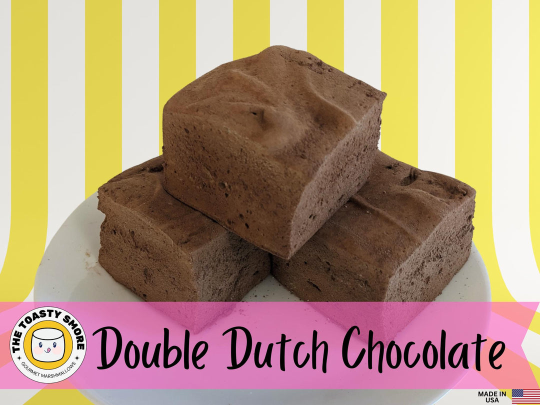 Three Double Dutch chocolate marshmallows on a plate, displayed on a yellow and white striped background. The image features The Toasty Smore logo and a "Made in USA" flag