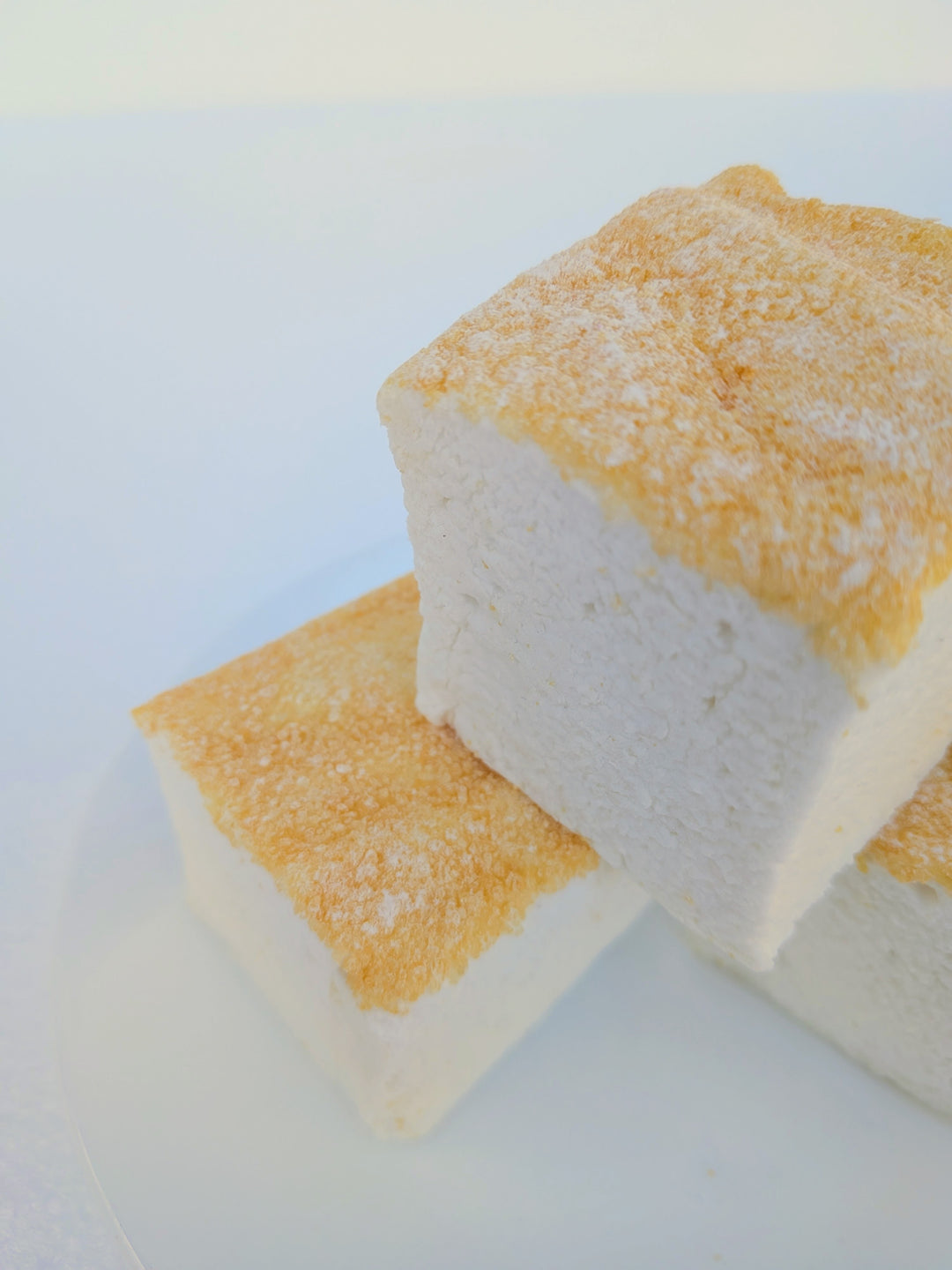 Three fluffy Piña Colada marshmallows with toasted tops on a white plate, made with beef gelatin and organic marshmallow root; clean‑label, corn‑syrup free real marshmallows.