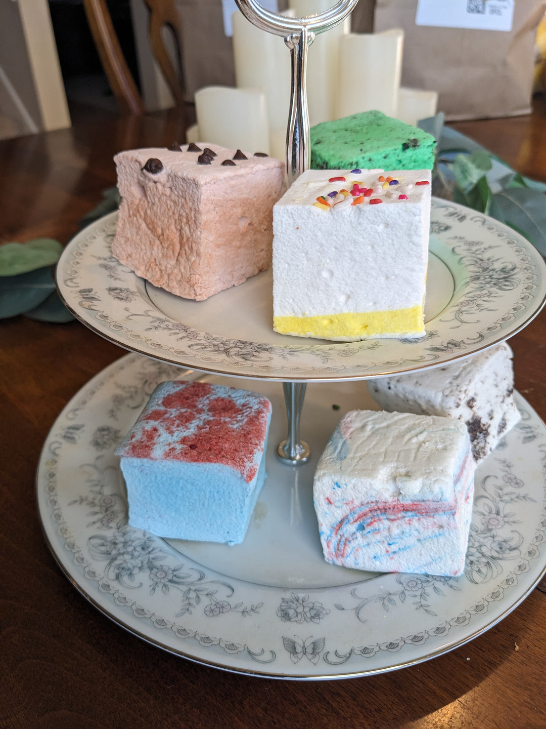 A tiered fancy plate featuring a vibrant assortment of birthday-themed marshmallows in flavors: birthday cake, cotton candy, blue raspberry, cookie dough, cookies & cream, and mint oreo.
