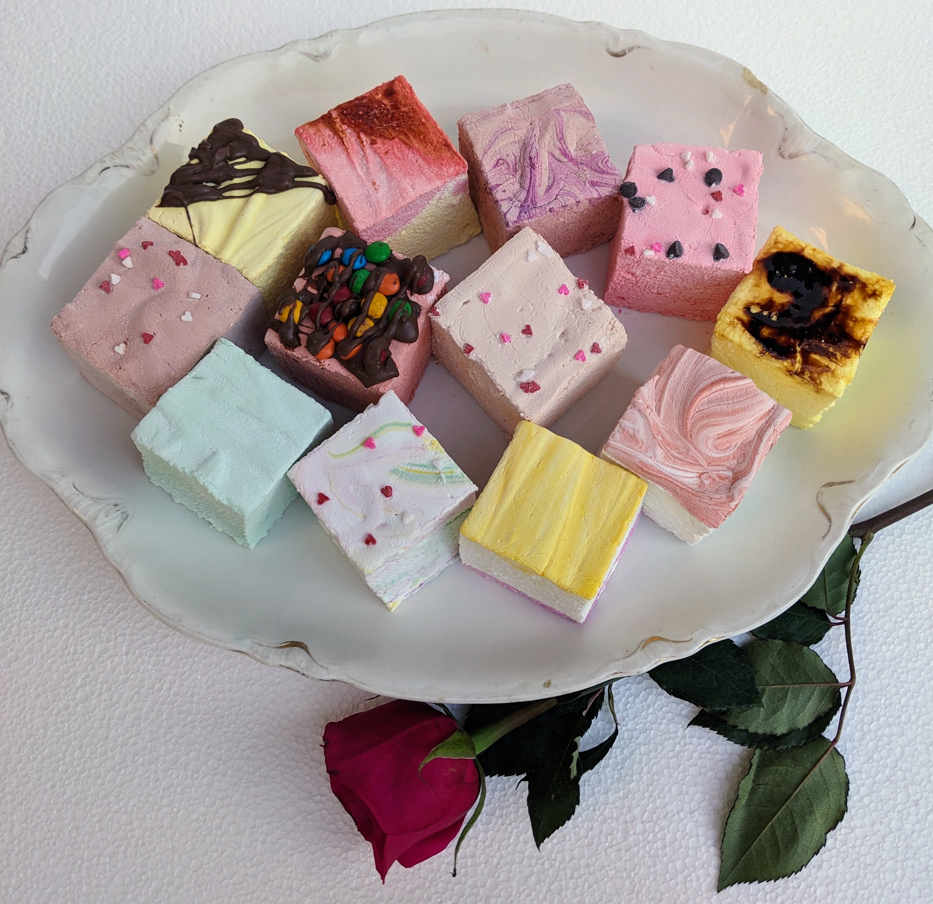 A plate of gourmet marshmallows, including flavors creme brulee, peanut butter, salted caramel, butter vanilla, mint, tutti frutti, banana split, toasted strawberry cheesecake, dulce de leche, wild cherry chip, amaretto, and double Dutch chocolate.