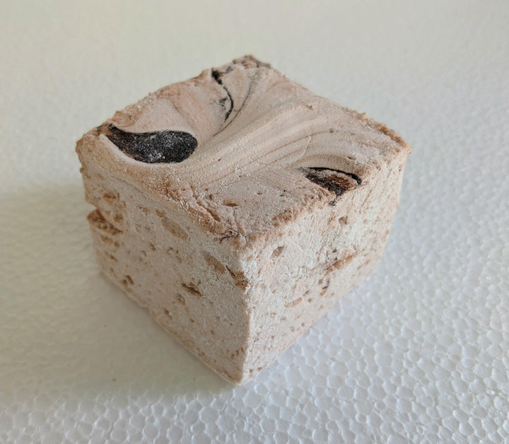 A single handcrafted gourmet Dulce De Leche marshmallow, neatly placed on a white plate and displayed against a plain white background