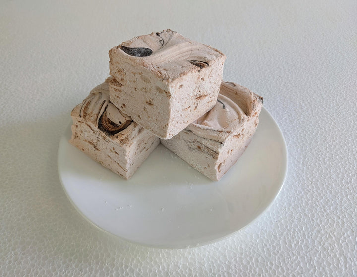 Three handcrafted gourmet Dulce De Leche marshmallows, neatly arranged on a white plate and displayed against a plain white background. Each marshmallow is approximately 2" x 2" x 2", crafted with high-quality  gelatin. By The Toasty Smore