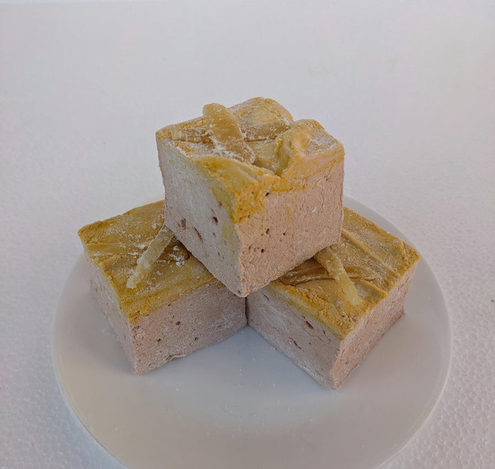Three handcrafted gourmet gingerbread marshmallows, neatly placed on a white plate and displayed against a plain white background. Each marshmallow is approximately 2" x 2" x 2", crafted with high-quality gelatin.