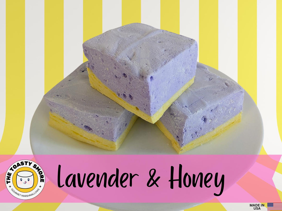 Watch a plate of three handcrafted gourmet lavender & honey marshmallows on a vibrant yellow and white striped background. The video showcases their soft, fluffy texture and delicate floral flavor. The Toasty Smore logo and a "Made in USA" flag are prominently displayed, emphasizing the artisanal quality and craftsmanship.