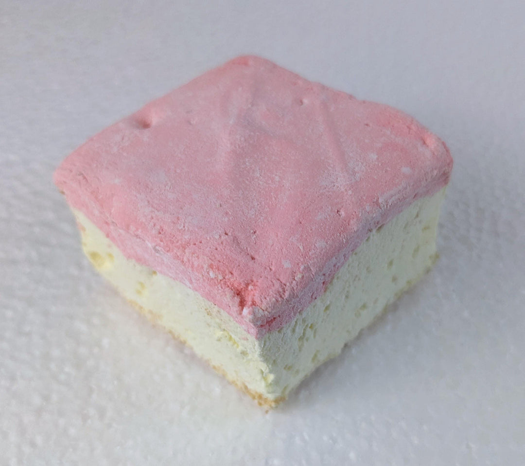 A single handcrafted gourmet strawberry cheesecake marshmallow displayed on a clean white background. The marshmallow is approximately 2" x 2" x 2", showcasing its soft, fluffy texture and rich cheesecake flavor with strawberry accents.