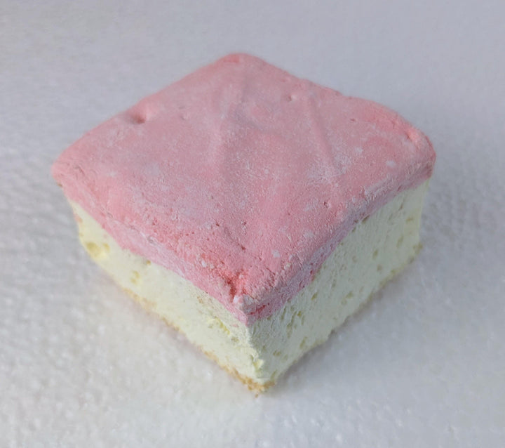 A single handcrafted gourmet strawberry cheesecake marshmallow displayed on a clean white background. The marshmallow is approximately 2" x 2" x 2", showcasing its soft, fluffy texture and rich cheesecake flavor with strawberry accents.