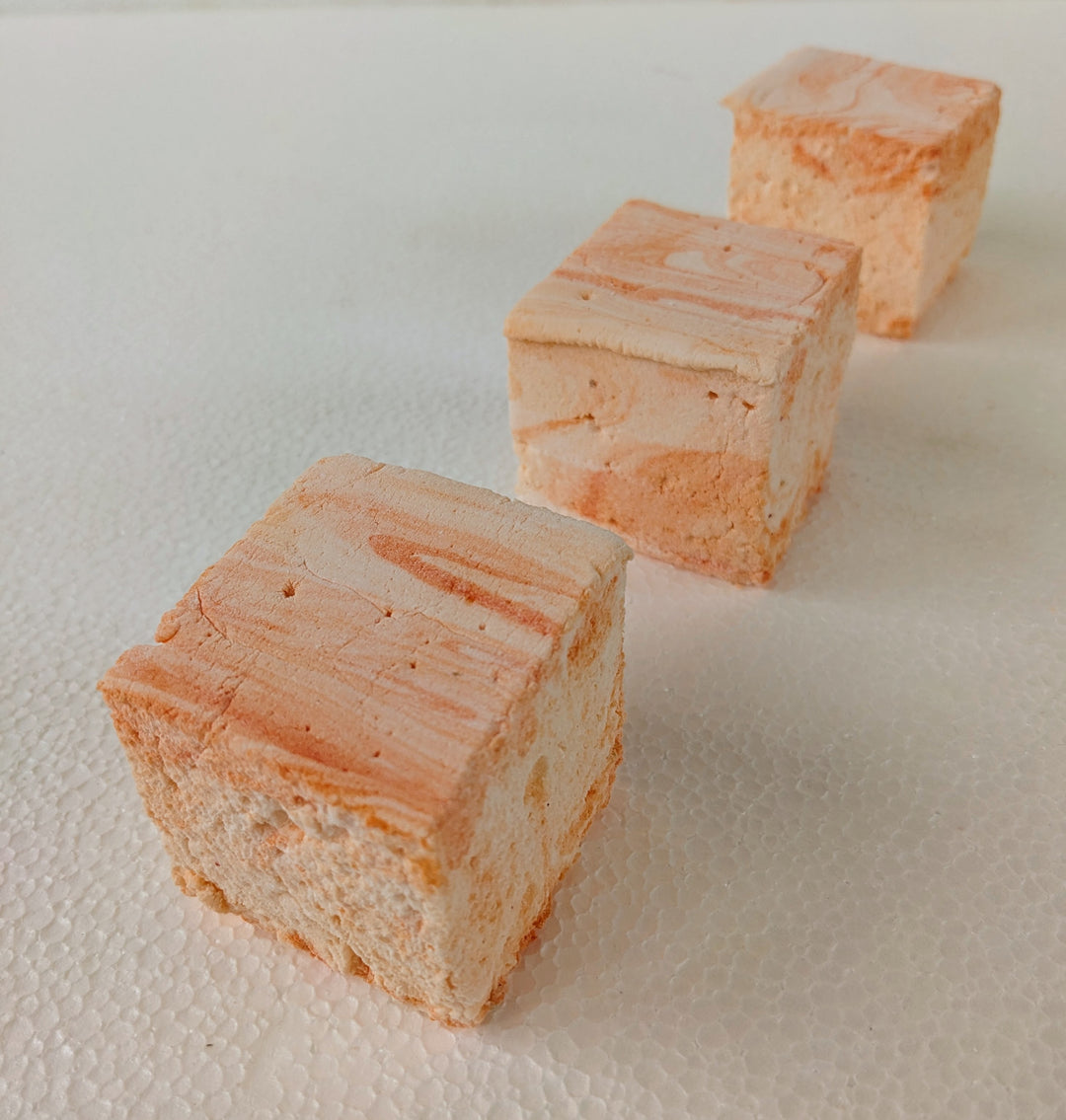 Three handcrafted salted caramel gourmet marshmallows aligned in a perfect row on a crisp white background, showcasing their delicate golden caramel swirls and pillowy texture. These artisan confections offer a rich, sweet-and-salty indulgence, ideal for luxury dessert lovers seeking premium treats.