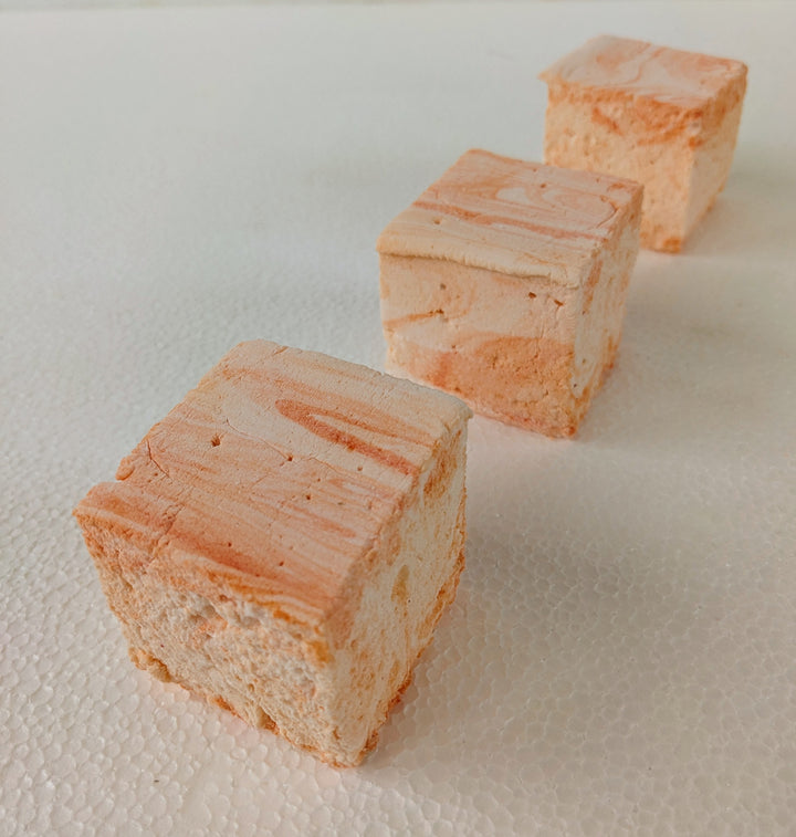 Three handcrafted salted caramel gourmet marshmallows aligned in a perfect row on a crisp white background, showcasing their delicate golden caramel swirls and pillowy texture. These artisan confections offer a rich, sweet-and-salty indulgence, ideal for luxury dessert lovers seeking premium treats.