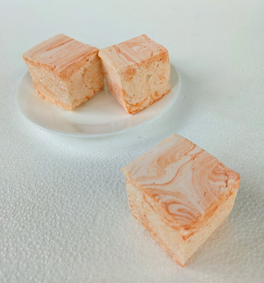 Three handcrafted salted caramel gourmet marshmallows displayed on a pristine white background, with one positioned in the foreground and two slightly behind. The rich, golden caramel swirls highlight their pillowy texture, creating a visually irresistible artisan treat perfect for luxury dessert lovers.