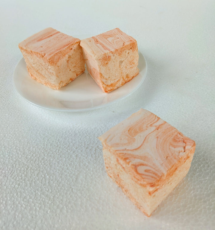 Three handcrafted salted caramel gourmet marshmallows displayed on a pristine white background, with one positioned in the foreground and two slightly behind. The rich, golden caramel swirls highlight their pillowy texture, creating a visually irresistible artisan treat perfect for luxury dessert lovers.