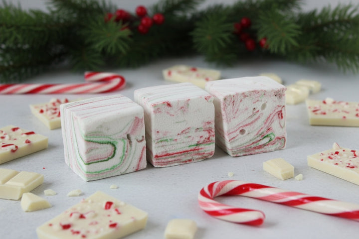 White Chocolate Peppermint Bark marshmallows by The Toasty S’more styled with crushed candy canes, white chocolate shards, and festive Christmas branches on a bright white background. Handcrafted with beef gelatin and organic marshmallow root for a corn-syrup free, clean-label seasonal indulgence.