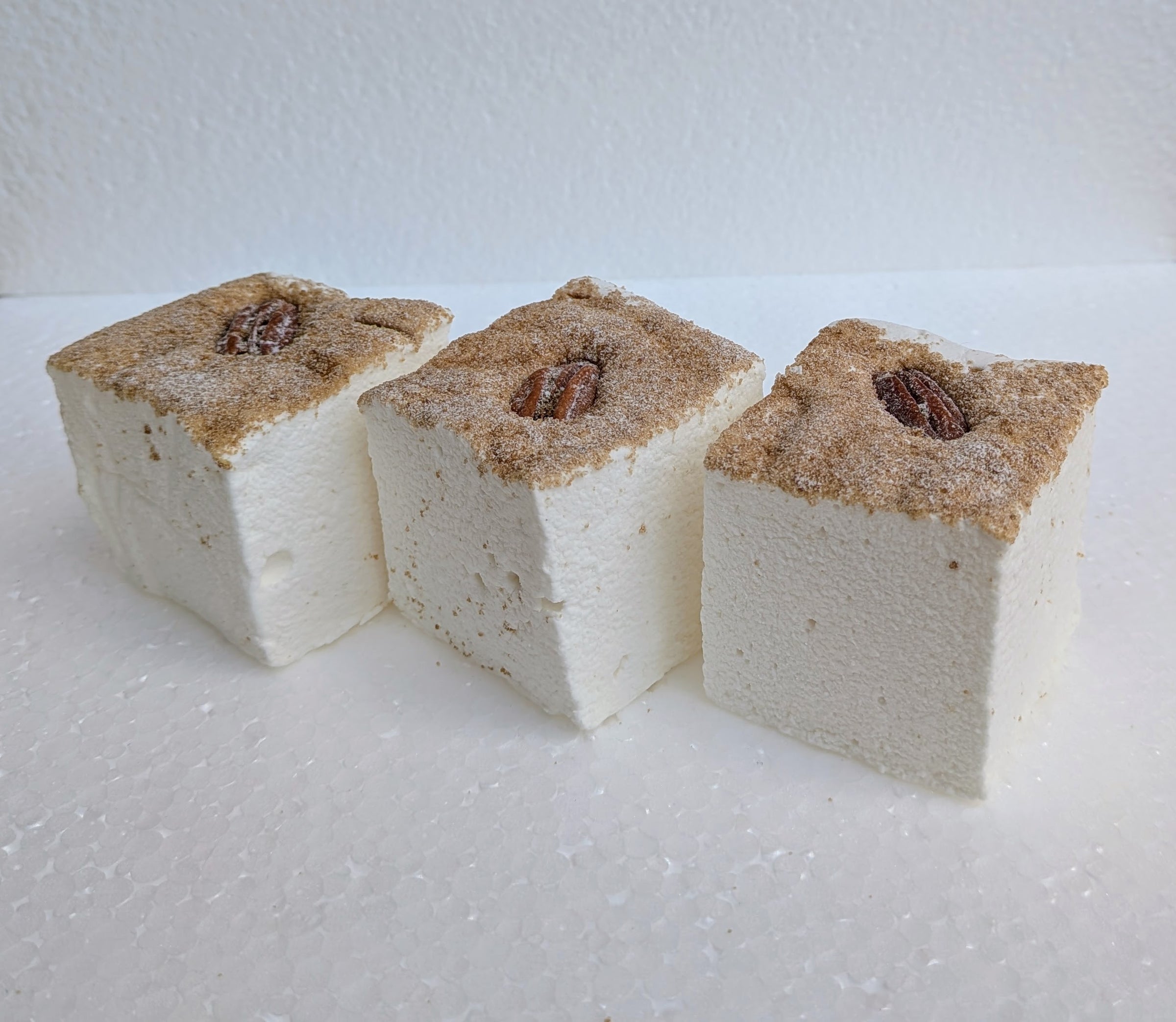 Three maple pecan pie marshmallows made with beef gelatin, organic marshmallow root, and no corn syrup, displayed on a clean white background. Each handcrafted marshmallow is topped with a whole pecan and a dusting of cinnamon sugar, showcasing their seasonal flavor and artisanal quality