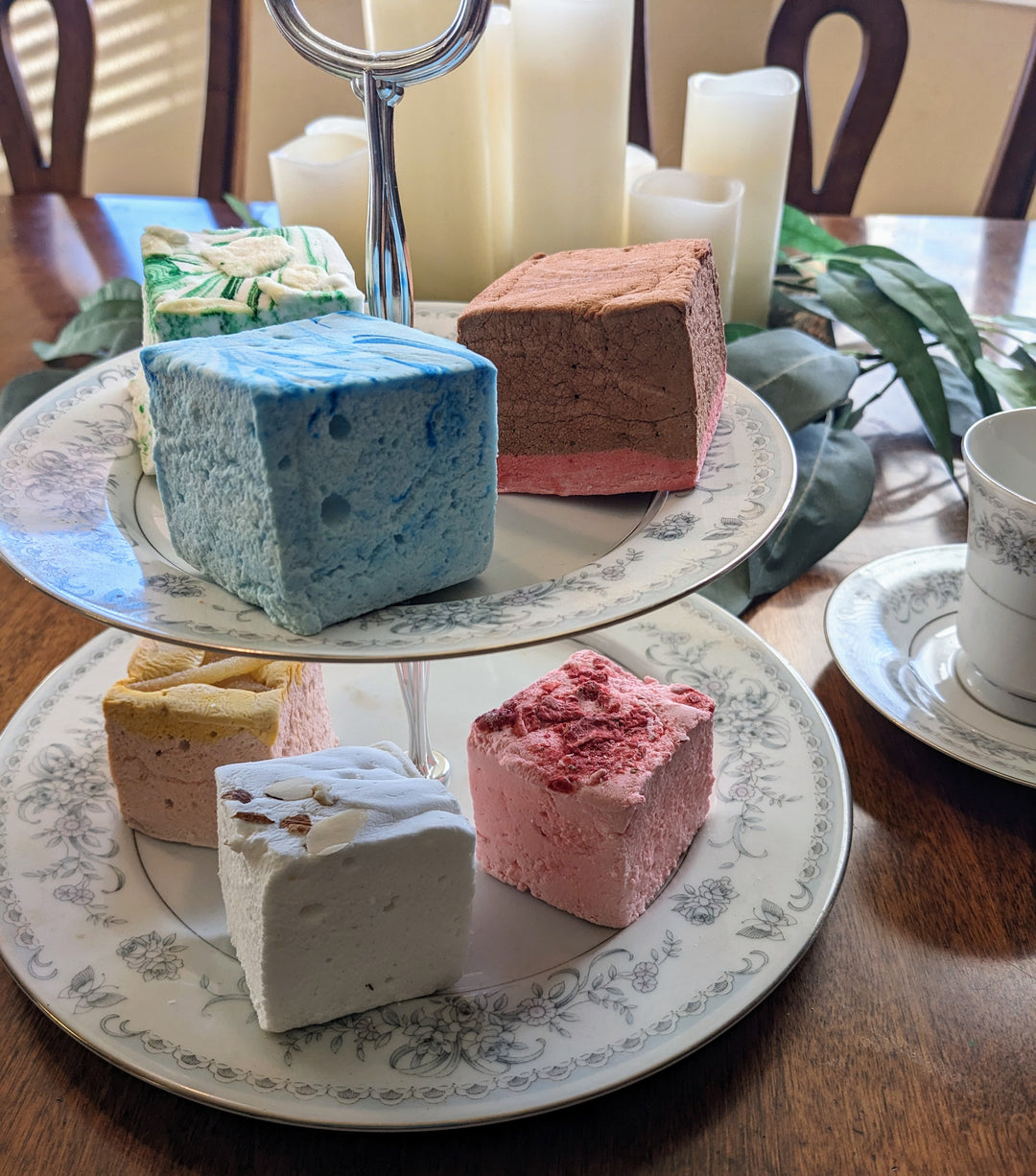 A tantalizing selection of our Medieval Delight Bundle marshmallows elegantly displayed on a two-tiered fancy plate. Featuring flavors like Red Rose Pudding, Gingerbread, Almond Cake, Junket with Blueberries, Pears in Wine Syrup, and Strawberries in White Custard Sauce