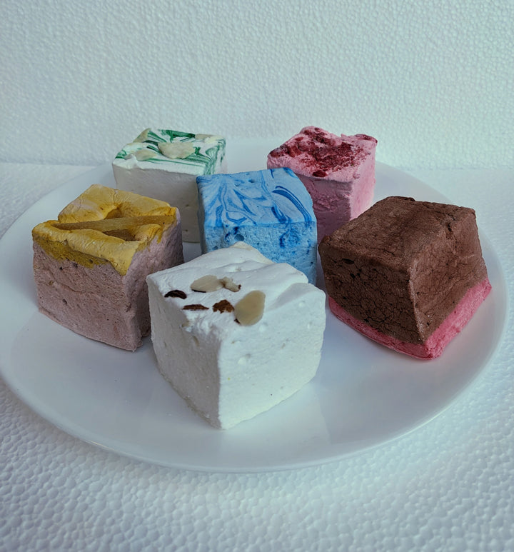 An enticing selection of our Medieval Delight Bundle marshmallows elegantly displayed on a two-tiered fancy plate. Featuring flavors like Red Rose Pudding, Gingerbread, Almond Cake, Junket with Blueberries, Pears in Wine Syrup, and Strawberries in White Custard Sauce