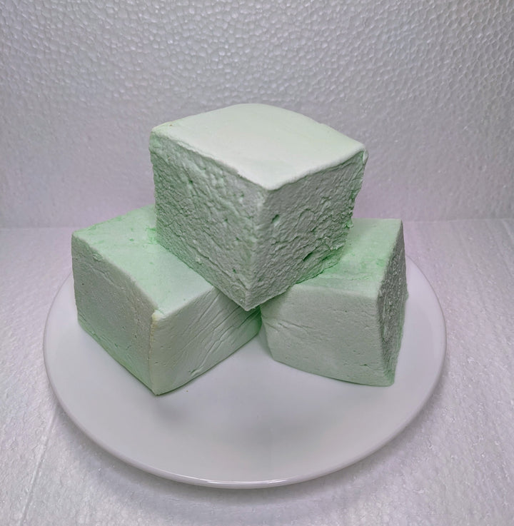 Three mint green marshmallows on a white plate, displayed on a clean, white background. The marshmallows, made with premium gelatin no corn syrup