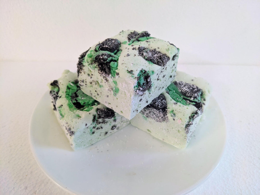 Three mint green marshmallows with Oreo crumbs on a plain white background.