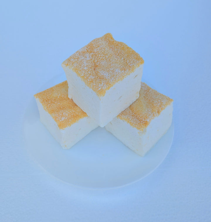 Three fluffy Piña Colada marshmallows on a white plate with toasted tops, made with beef gelatin and organic marshmallow root; clean‑label, corn‑syrup free real marshmallows.