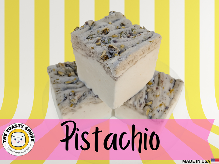 Three pistachio marshmallows with beef gelatin and organic marshmallow root, stacked on a white plate against a striped yellow background with pink overlay. Clean-label, corn syrup-free, gluten-free, and made in the USA.