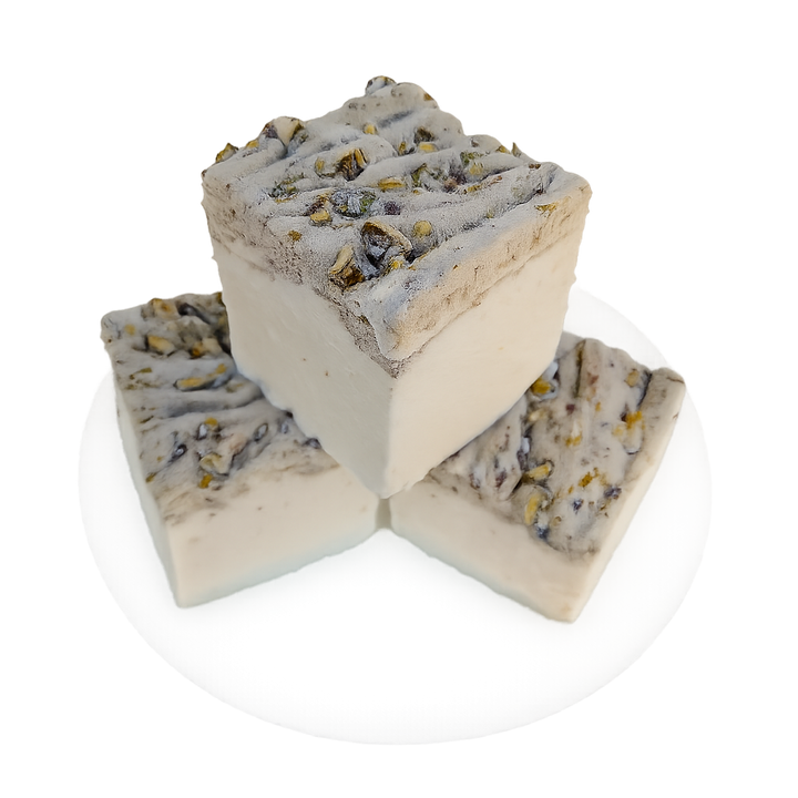 Three pistachio marshmallows made with beef gelatin and organic marshmallow root, arranged on a white plate with one piece standing upright on top of three. The clean-label marshmallows have a white base and a textured pistachio‑studded top, photographed against a plain background.