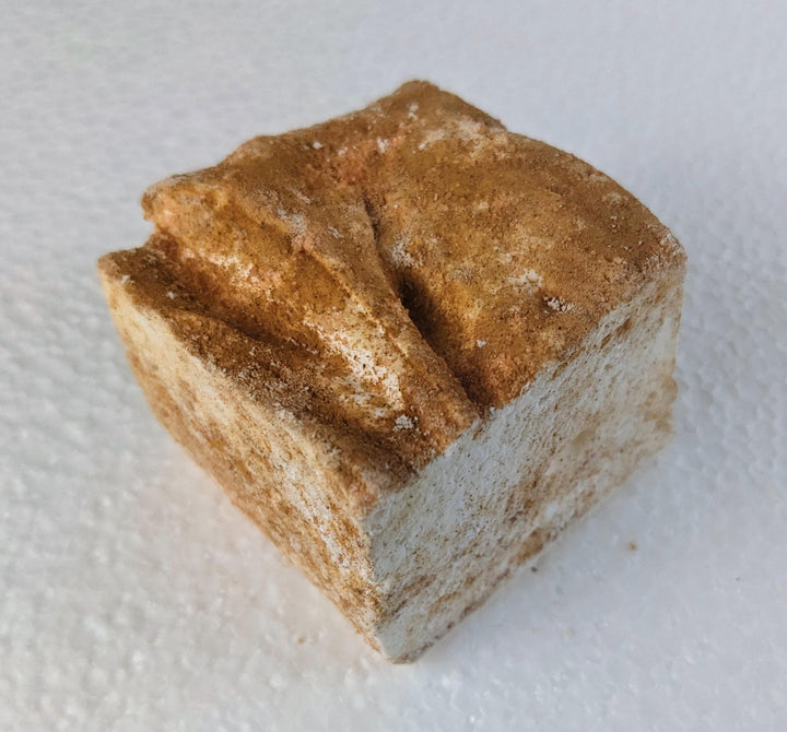 A single caramel churro marshmallow on a white plate, displayed on a plain white background.
