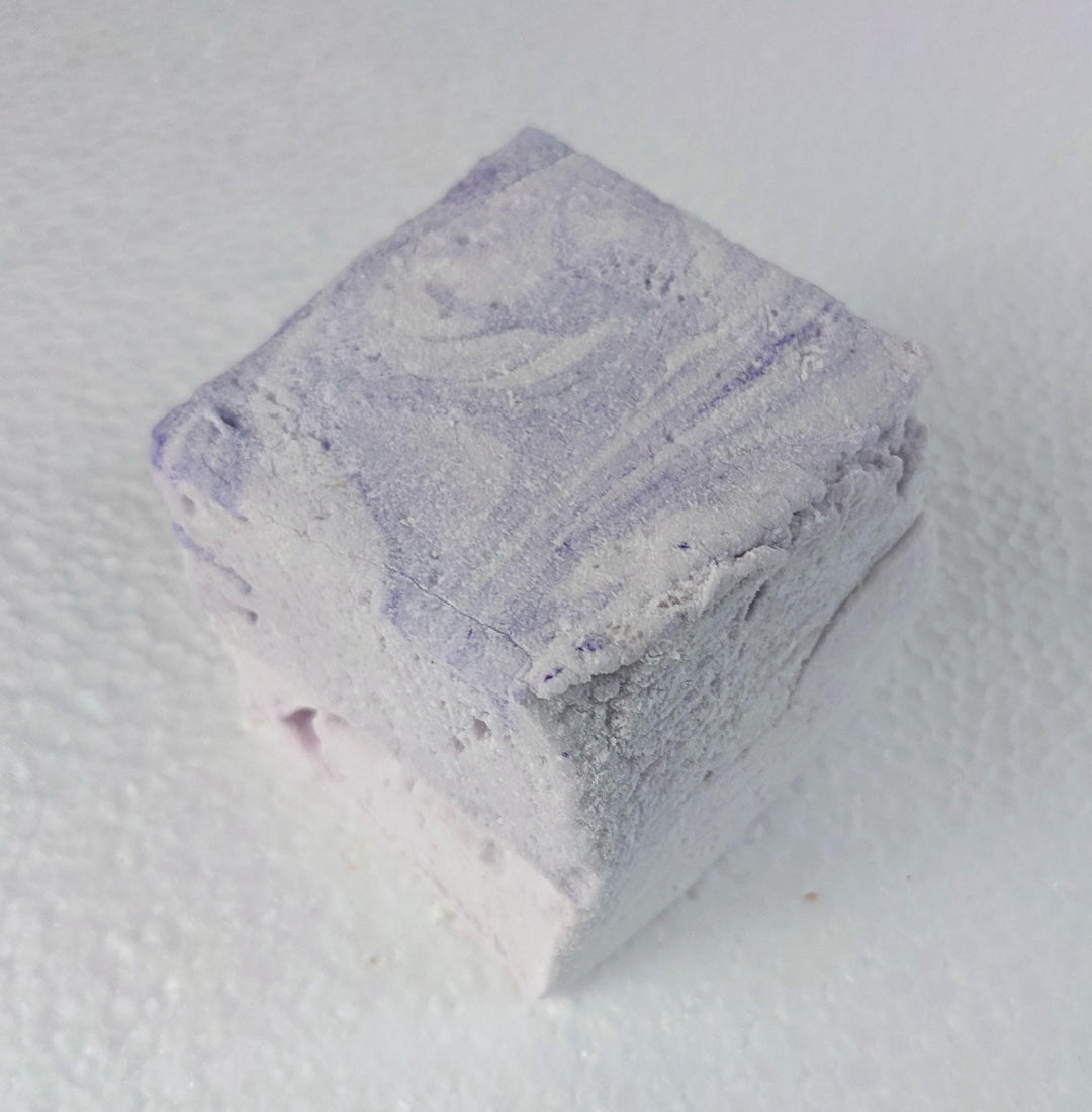 A single creamy purple taro marshmallow on a white plate, displayed on a plain white background.