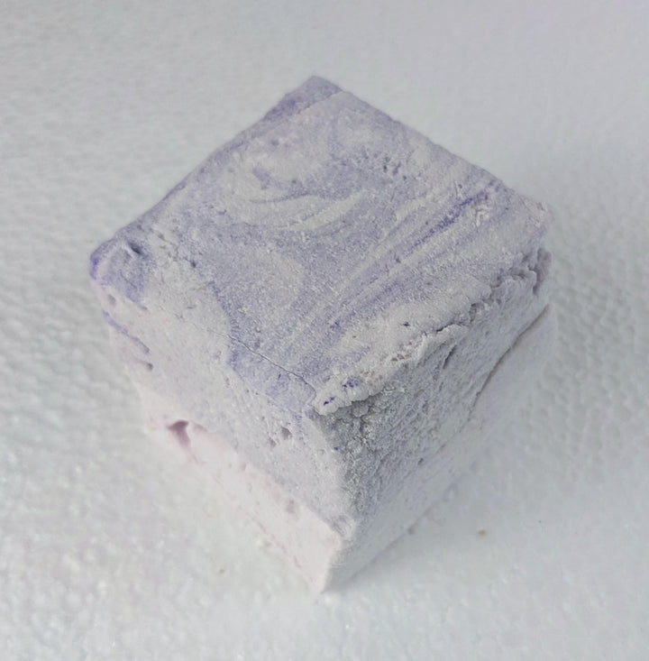 A single creamy purple taro marshmallow on a white plate, displayed on a plain white background.