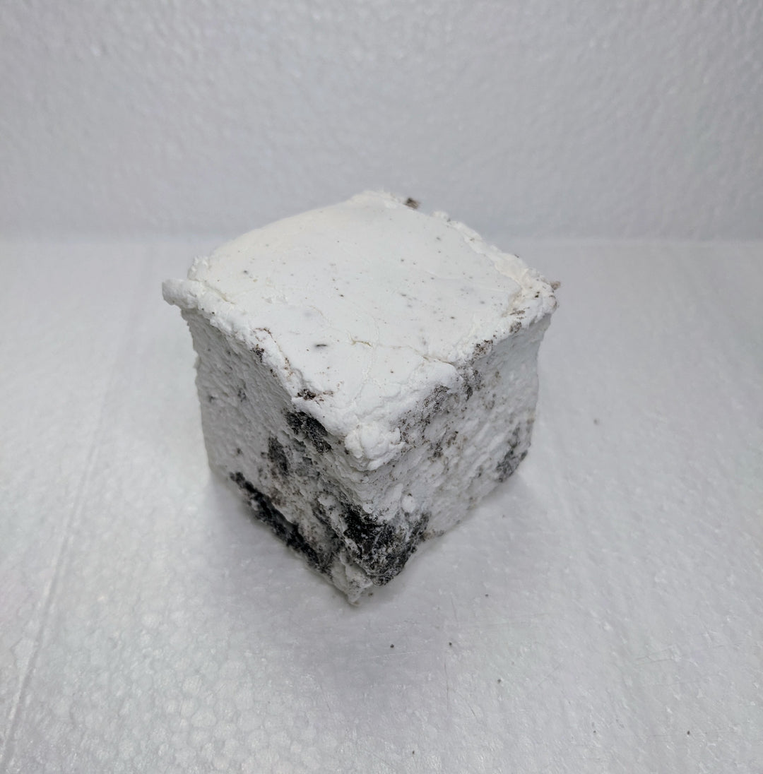 A single handcrafted gourmet cookies & cream marshmallow on a white plate, displayed on a plain white background. The marshmallow is approximately 2" x 2" x 2" and made from premium gelatin.