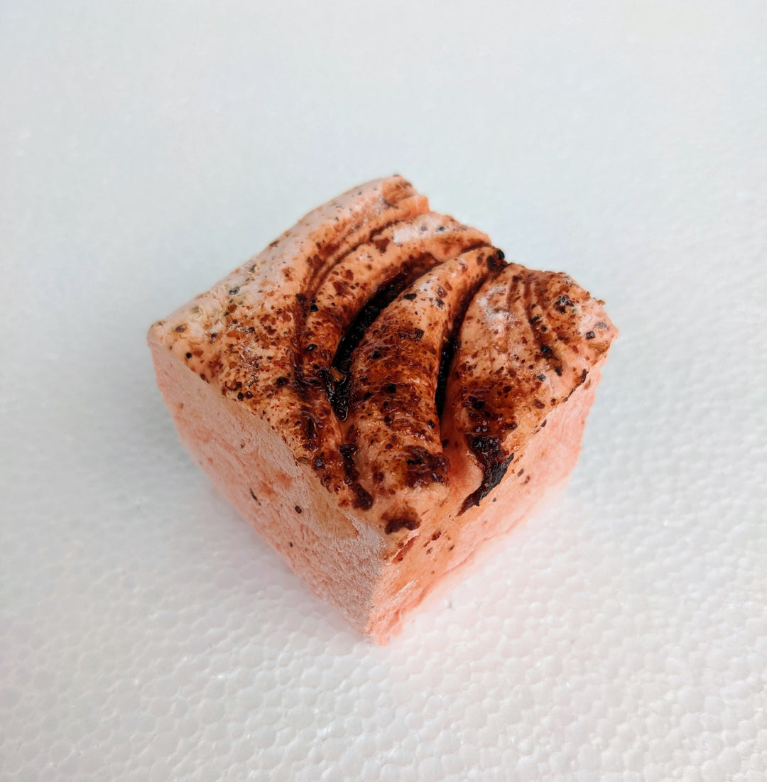 A single vibrant orange mango chamoy marshmallow on a white plate, displayed on a plain white background.