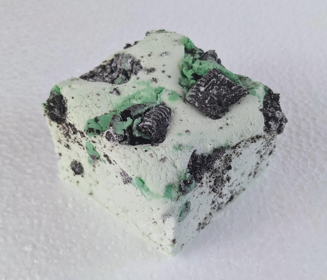 A single mint green marshmallow with Oreo crumbs on a white plate, displayed on a plain white background.