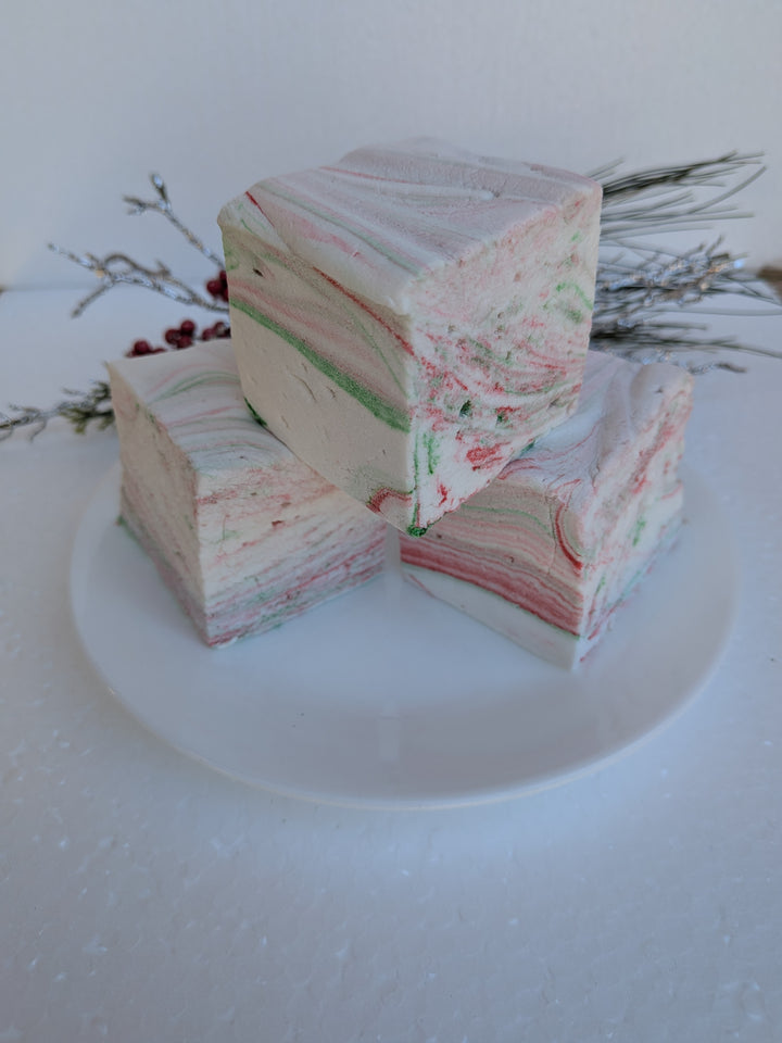Stack of three White Chocolate Peppermint Bark marshmallows by The Toasty S’more, styled with festive Christmas branches against a white background. Handcrafted, corn-syrup free, and made with beef gelatin and organic marshmallow root for a clean-label holiday treat.