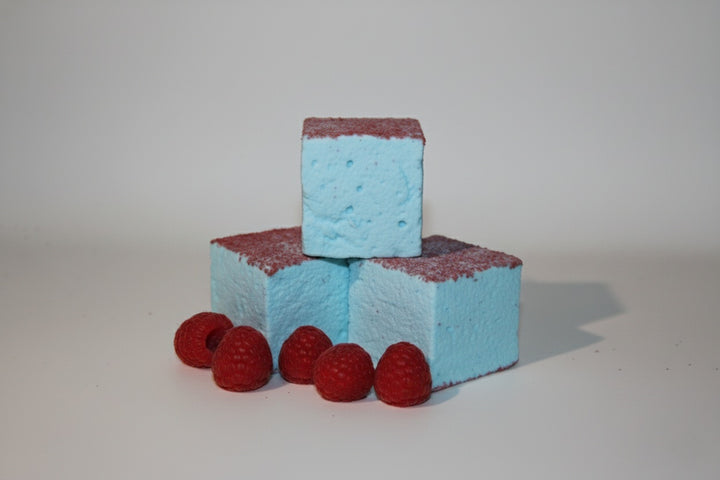 Three blue raspberry gourmet marshmallows made with beef gelatin and organic marshmallow root, stacked vertically without a plate. Each marshmallow features a bold blue base and red sugar topping, styled with fresh red raspberries nearby. Clean-label, corn syrup-free marshmallows crafted for vibrant flavor and festive presentation