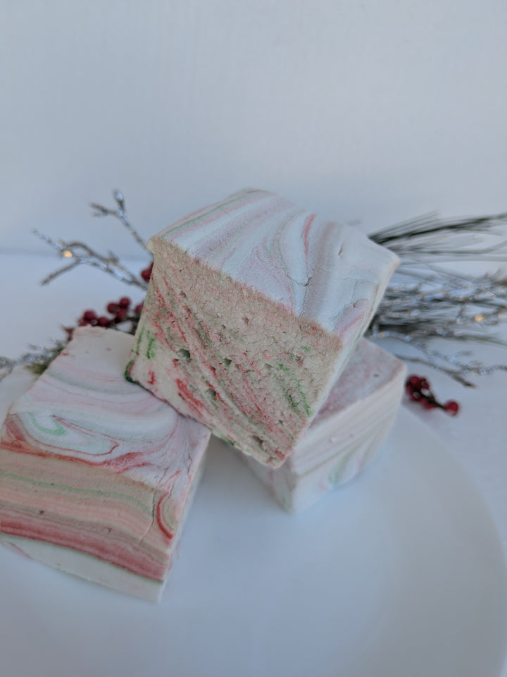 Three stacked White Chocolate Peppermint Bark marshmallows by The Toasty S’more, set against a white background with festive Christmas greenery. Handcrafted with beef gelatin and organic marshmallow root for a corn-syrup free, clean-label seasonal treat.