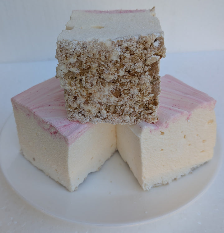 Three handcrafted strawberry cheesecake marshmallows made with natural colors, Halal‑certified beef gelatin, organic marshmallow root, and clean‑label ingredients, displayed on a clean white background; these corn‑syrup‑free, real marshmallows show a soft, fluffy texture with rich cheesecake flavor and strawberry accents.