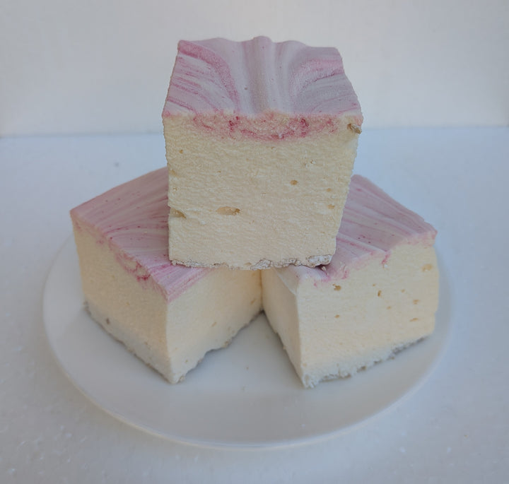 Three handcrafted strawberry cheesecake marshmallows made with natural colors, Halal‑certified beef gelatin, organic marshmallow root, and clean‑label ingredients, arranged on a white plate; these corn‑syrup‑free real marshmallows show a soft, fluffy texture with rich cheesecake flavor and strawberry accents.