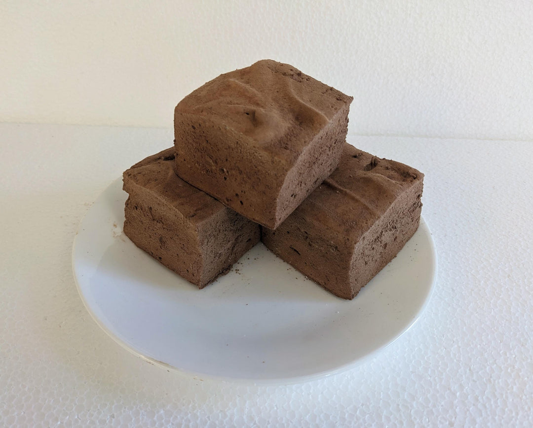 Three Double Dutch Chocolate flavored marshmallows, displayed on a clean, white background. Each marshmallow has a rich, dark brown hue, embodying the decadent and indulgent nature of chocolate. The soft, fluffy texture and uniform shape of the marshmallows emphasize the artisanal quality and delightful appearance of these gourmet treats.