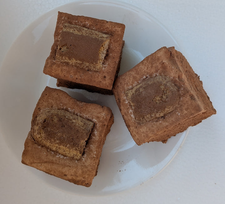 Three square Tiramisu Gourmet Marshmallows with a layer of a different color on a white plate