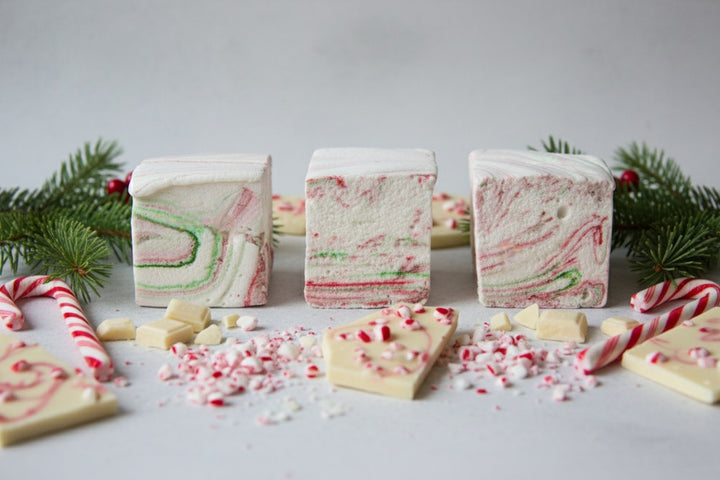 White Chocolate Peppermint Bark marshmallows by The Toasty S’more styled with crushed candy canes, white chocolate pieces, and festive Christmas greenery on a clean white background. Handcrafted with beef gelatin and organic marshmallow root for a corn-syrup free, clean-label holiday indulgence.